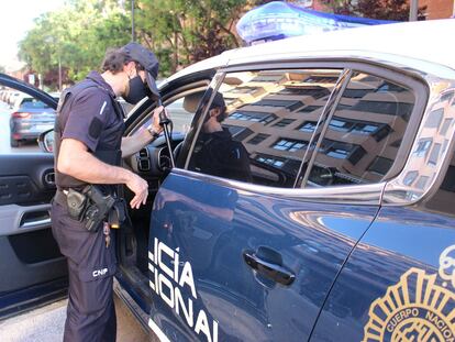 Un agente de la Policía Nacional junto a un coche patrulla.