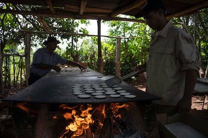 Julio César Núñez y su sobrino cocinan casabe en un comal de leña en Quivicán, Cuba