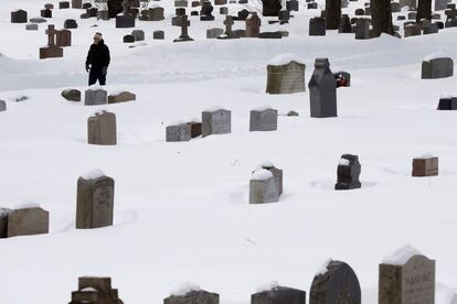 A man walks among snow-covered tombstones at St. Paul's Cemetery in Arlington, Massachusetts, February 18, 2015, following a series of winter snowstorms in the Boston area. The aftermath of a deadly winter storm paralyzed much of the eastern U.S. on Tuesday and forecasters warned of the worst cold in two decades from another arctic front this week. REUTERS/Brian Snyder (UNITED STATES - Tags: ENVIRONMENT)