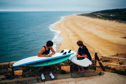 Dos jóvenes con sus tablas de surf observan la Praia do Norte desde el fuerte de São Miguel Arcángel (Portugal), el pasado 29 de julio. 
