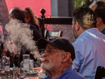 Un cliente de El Gran León de Oro, una cantina amparada contra la nueva Ley Antitabaco, fuma un puro mientras juega al dominó en la terraza del establecimiento.