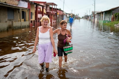 Residentes caminan por una calle inundada tras el paso del huracán Rafael en Batabano, Cuba.