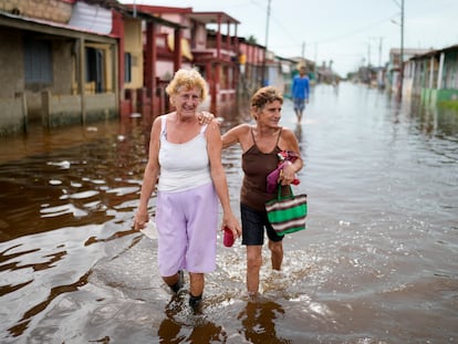 Residentes caminan por una calle inundada tras el paso del huracán Rafael en Batabano, Cuba.