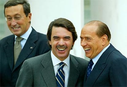 Berlusconi saluda a Aznar ante la mirada de Gianfranco Fini, a su llegada al Palacio de Congresos de Roma.