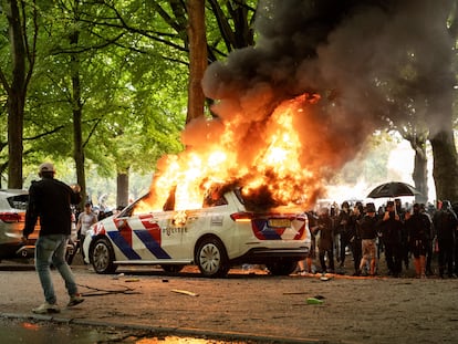 Un coche policial en llamas durante la protesta contra la inmigración en La Haya