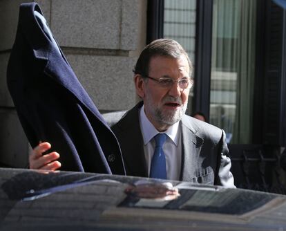 El presidente del Gobierno, Mariano Rajoy, agarra su abrigo antes de meterse en el coche una vez terminada la segunda jornada de la sesión del debate del estado de la nación.