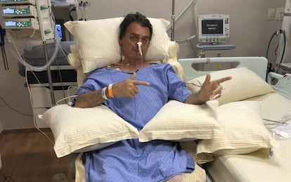 O candidato Jair Bolsonaro faz o famoso sinal de metralhadora para mostrar sua recuperação no hospital Albert Einstein de São Paulo.