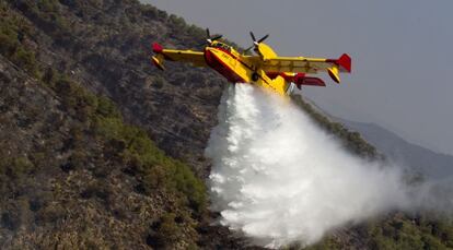 Un avión de los equipos de extinción descarga agua sobre la zona del incendio que afecta a tres municipios de Valencia.
