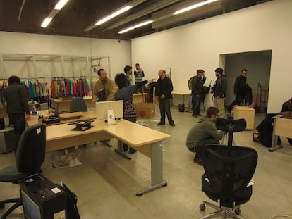 Empleados de Kukuxumusu, montadores y fotógrafos trabajan para crear un ambiente de oficina dentro de una galería de arte.