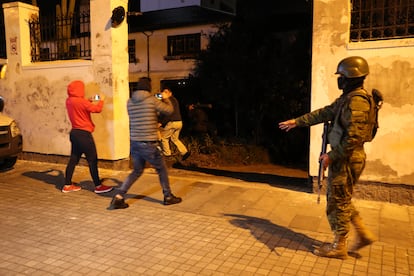 Journalists film police officers as they enter the Mexican Embassy grounds.
