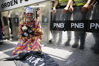 Una opositora del gobierno vistiendo un traje tradicional Wayuu se arrodilla frente a la policía antidisturbios que intenta evitar que la marcha de mujeres llegue a la Cancillería en Caracas, el 6 de mayo de 2017. 