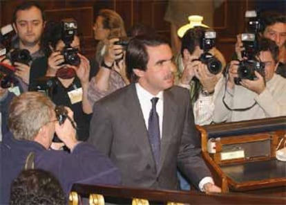 José María Aznar, rodeado de fotógrafos, se dirige a la tribuna del Congreso para hacer su intervención.