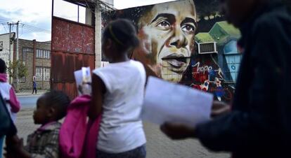 Personas caminan en Nairobi frente a un graffiti de Obama.