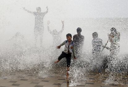 Crianças indianas se molham com as ondas que atingem a costa durante a maré Arábigo em Mumbai (Índia), no dia 6 de julho.