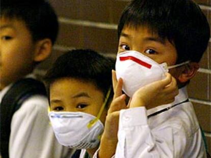 Dos niños se protegen con mascarillas en una escuela de Hong Kong.