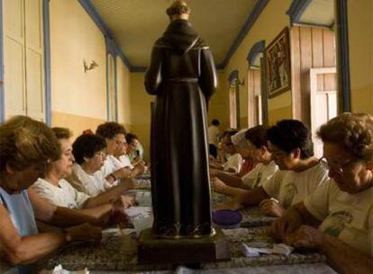 Un grupo de mujeres preparan las imágenes de Galvao, que será canonizado durante esta visita.