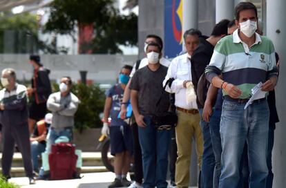 Un grupo de personas con mascarillas espera en la cola para entrar a un banco en Bogotá este lunes.