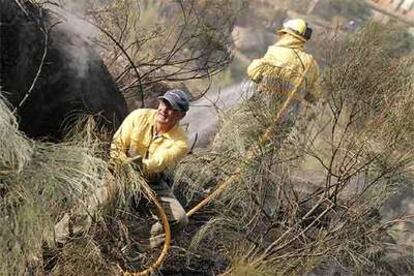 Dos bomberos ayudan a extinguir un incendio registrado la semana pasada en la provincia de Ávila.