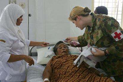 Personal sanitario australiano atiende a una mujer herida por el <i>tsunami</i> en la isla de Sumatra.