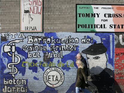 Una pareja pasa ante un mural de apoyo a ETA en Falls Road, en el barrio católico de Belfast.