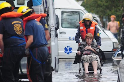 Una mujer es evacuada por un grupo de bomberos, 3 de abril de 2013, en La Plata (Argentina).
