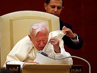 El Papa es ayudado a recolocarse su capa, levantada por el viento, ayer, durante el rezo del <b><i>ángelus</b></i> en Castel Gandolfo.