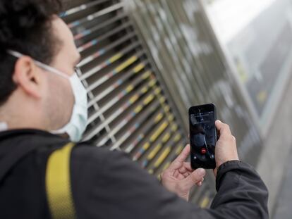 Un hombre protegido con mascarilla realiza una videollamada por su teléfono móvil, una de las formas más habituales de comunicarse durante la pandemia.