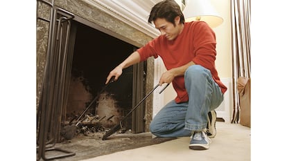 Una persona limpiando la chimenea apagada.
