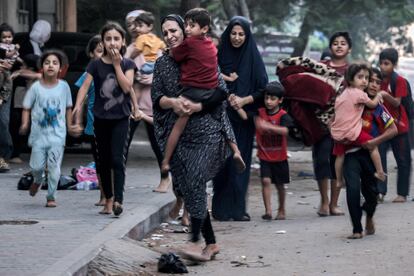 Unas mujeres con niños en brazos o de la mano caminan por una calle de Gaza el miércoles, huyendo de los bombardeos israelíes.  