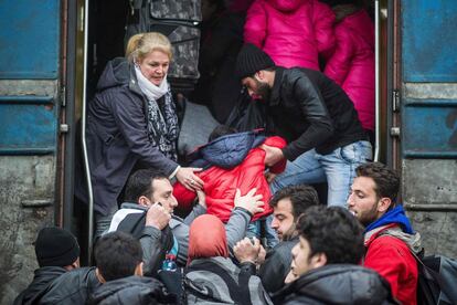 Un grupo de inmigrantes ayuda a un niño a subir a un tren que les llevará a Serbia.