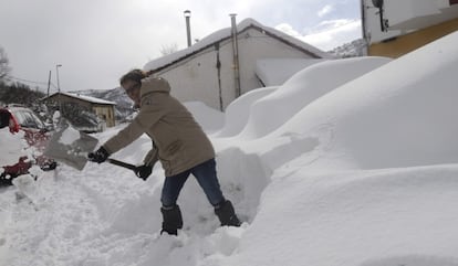 Un mujer retira nieve con una pala en Matallana de Torío (León).
