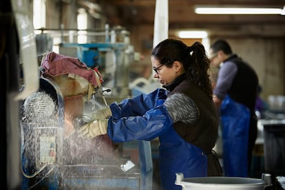 Una trabajadora recorta una jarra de cristal.