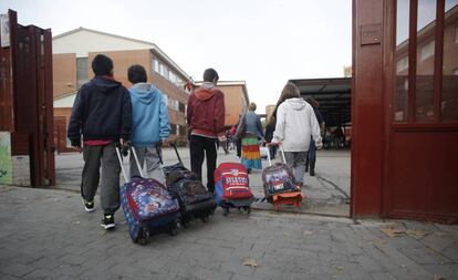 Varios niños arrastran sus mochilas al entrar en el colegio público La Latina en Aluche (Madrid).