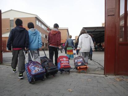 Varios niños arrastran sus mochilas al entrar en el colegio público La Latina en Aluche (Madrid).