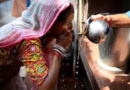 Un hombre hindú ofrece agua a una mujer en un templo de Nueva Delhi, en la India.