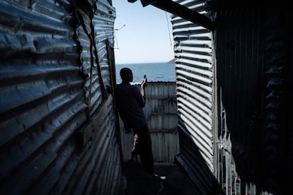 Un hombre habla por teléfono entre dos chabolas de hierro constuidas sobre el territorio de Migingo. La isla cuenta con algunos bares, burdeles y un pequeño puerto.