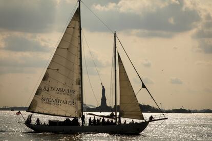 Un velero pasa por la Estatua de la Libertad en el puerto de Nueva York visto desde Battery Park, en la ciudad de Nueva York (EE UU).