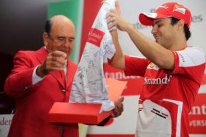 El presidente global del Banco Santander, Emilio Botín (i), entrega al piloto brasileño de Ferrari, Felipe Massa (d), una camiseta firmada por 100 estudiantes brasileños que se beneficiaron con becas ofrecidas por el Grupo Santander, a través del programa Fórmula Santander.