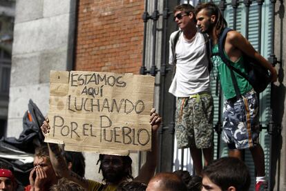 Un miembro del movimiento 15-M muestra un cartel que reza 'Estamos luchando por el pueblo'. Esa misma mañana, una indignada se ha 'colado' en el Congreso para entregar las propuestas del movimiento.