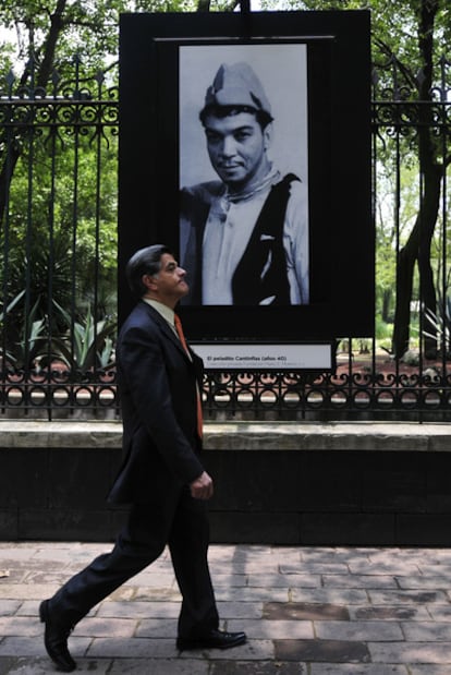 Un hombre camina en el Paseo de la Reforma de la ciudad de México frente a la exposición fotográfica Mario Moreno Cantinflas, en homenaje al comediante