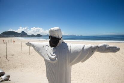 Um cristo com máscara na praia de Copacabana, que ficou deserta mesmo em dia de céu aberto.