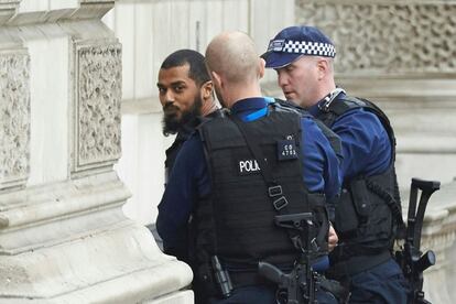 Dos policías detienen al joven frente al Parlamento.