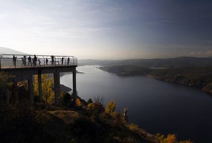 Turistas observan desde el mirador la Presa del Atazar al atardecer.