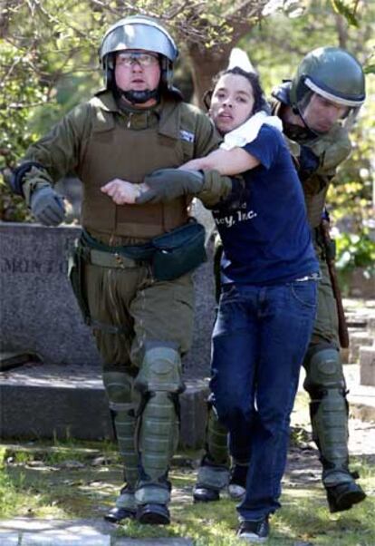 Dos policías antidisturbios detienen a un joven en Santiago.