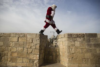 Un hombre vestido de Santa Claus camina por el muro de la Ciudad Vieja de Jerusalén.
