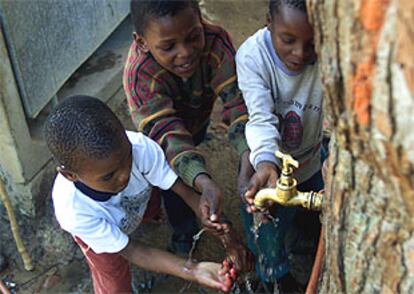 Niños surafricanos juegan en la fuente que abastece la comunidad Imizamo Yethu, cerca  de Ciudad del Cabo.