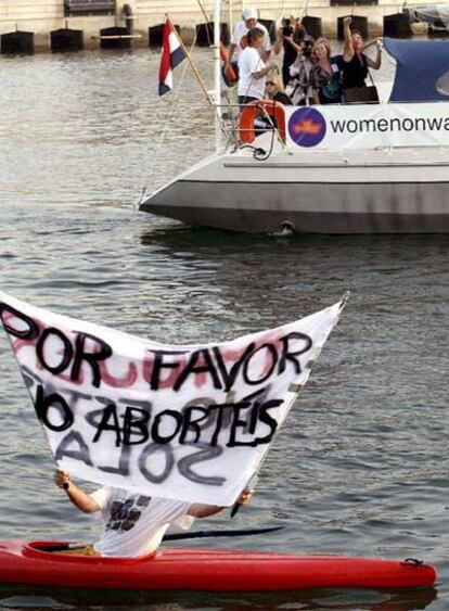 Una persona en piragua muestra una pancarta ante la llegada al puerto de Valencia del barco abortista.