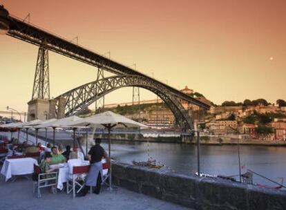 Terraza de una cafeteria junto al río Duero en el distrito de la Ribeira desde donde se ve el puente de Eiffel en Oporto Portugal
