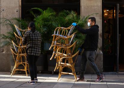 Dos trabajadores recogen la terraza de un bar del centro de Barcelona este viernes.