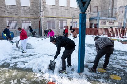 Grupo de padres voluntarios recogiendo nieve en el CEIP Victor Pradera de Leganés.
